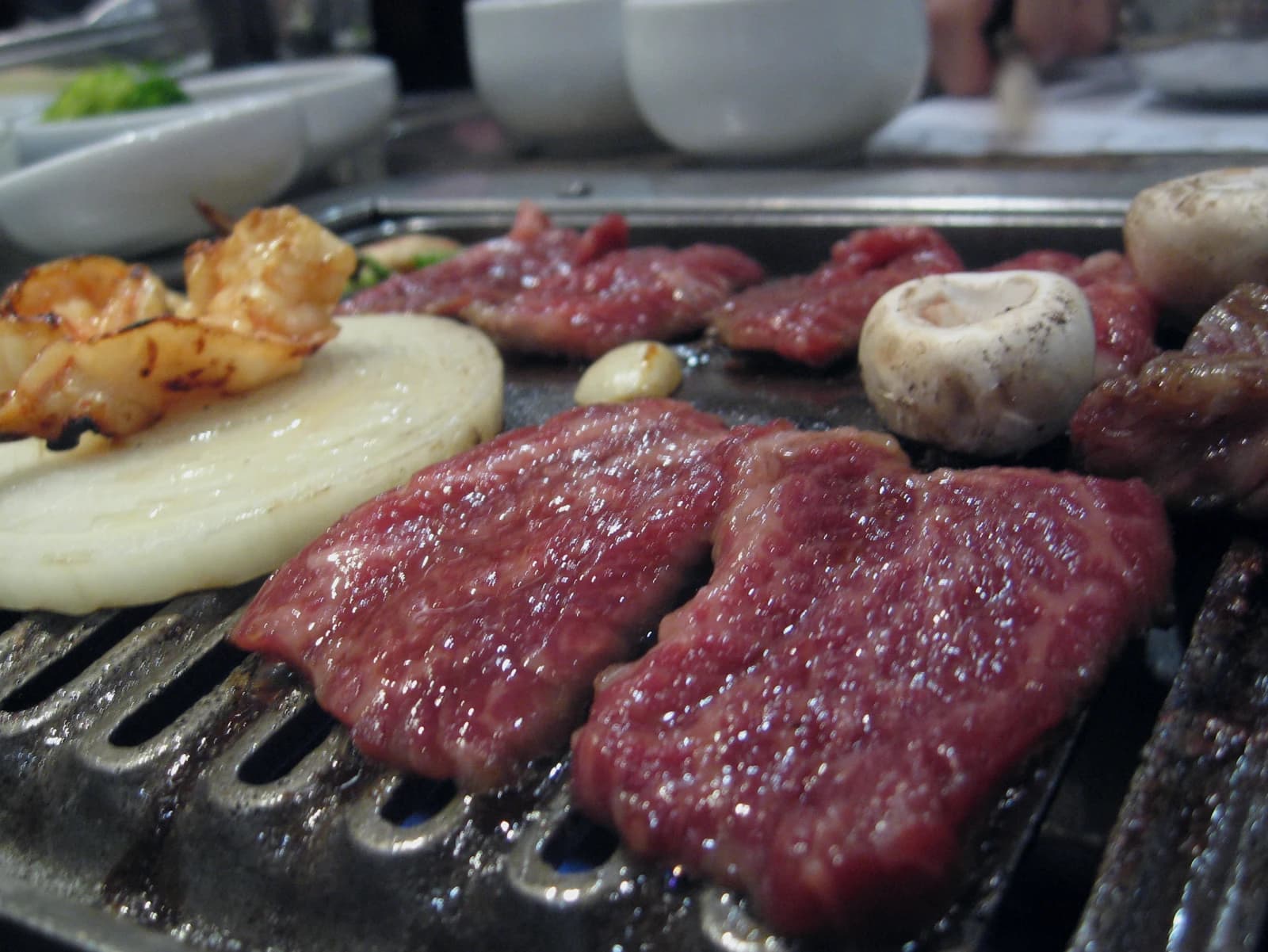 Korean BBQ meat grilling on a tabletop grill with banchan side dishes