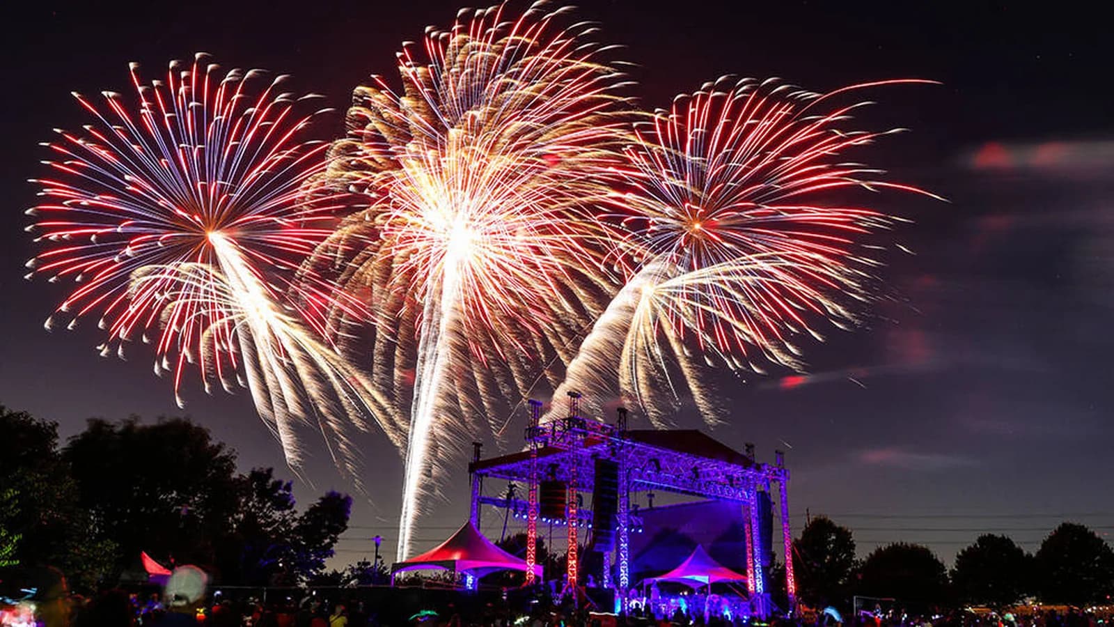 Fourth of July fireworks over a concert stage and crowd near Dallas